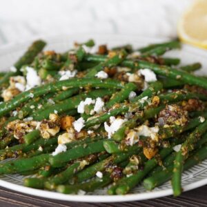 green beans on a plate with pesto and feta