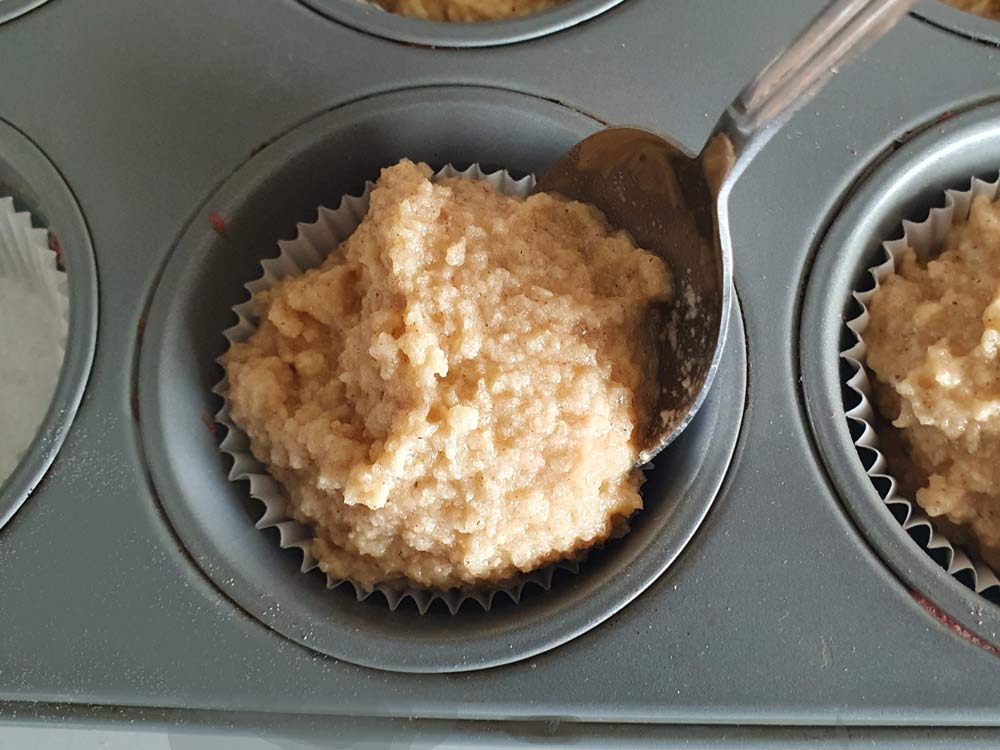 Spooning raw dough into a muffin tin