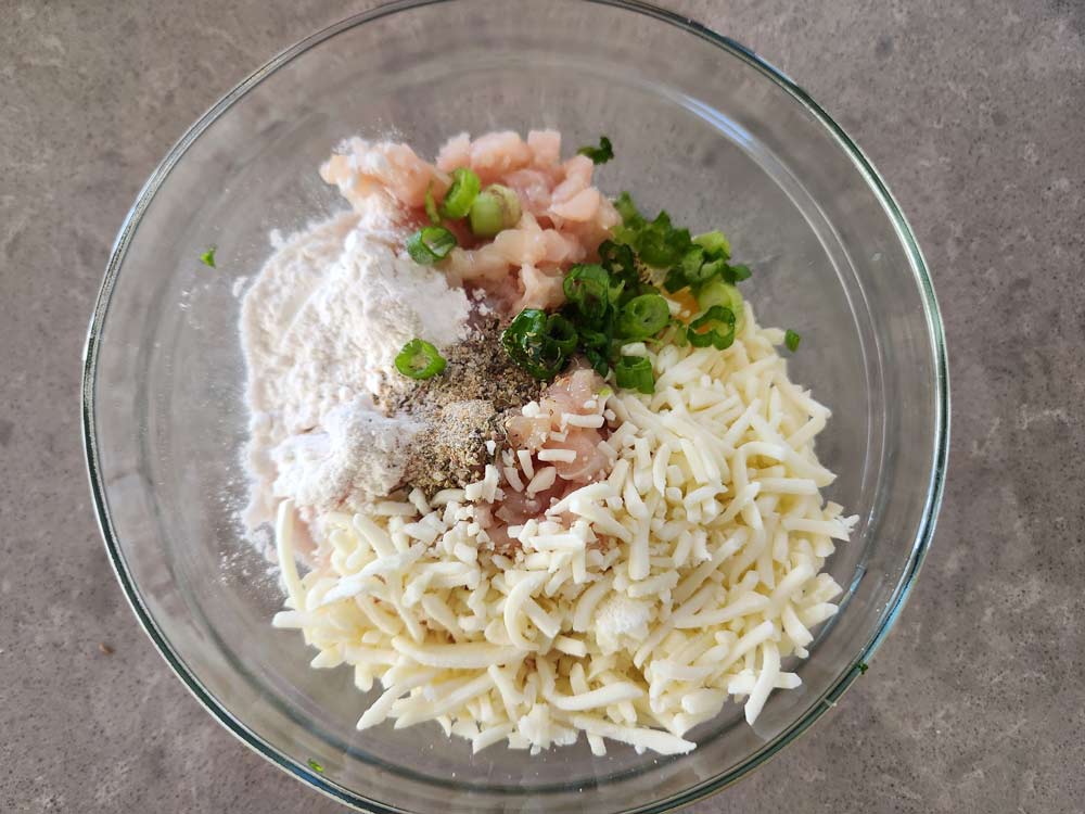 Mixing the ingredients for cheesy chicken fritters in a bowl