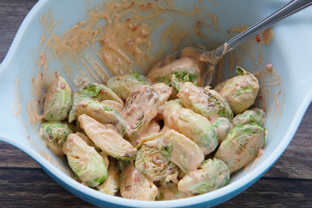 Mixing brussels sprouts with bang bang sauce