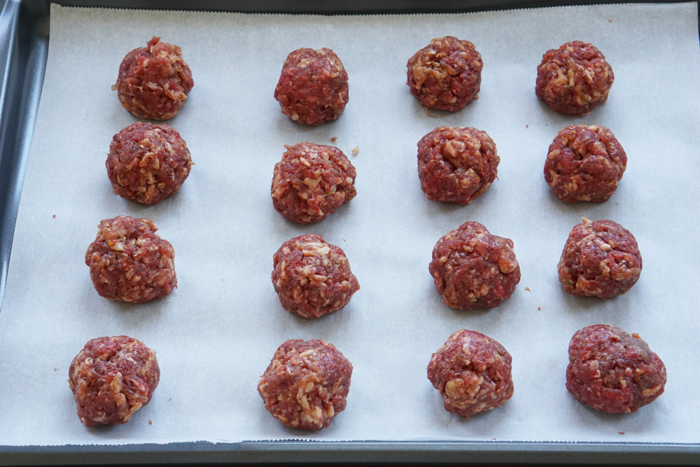 raw meatballs on a baking sheet