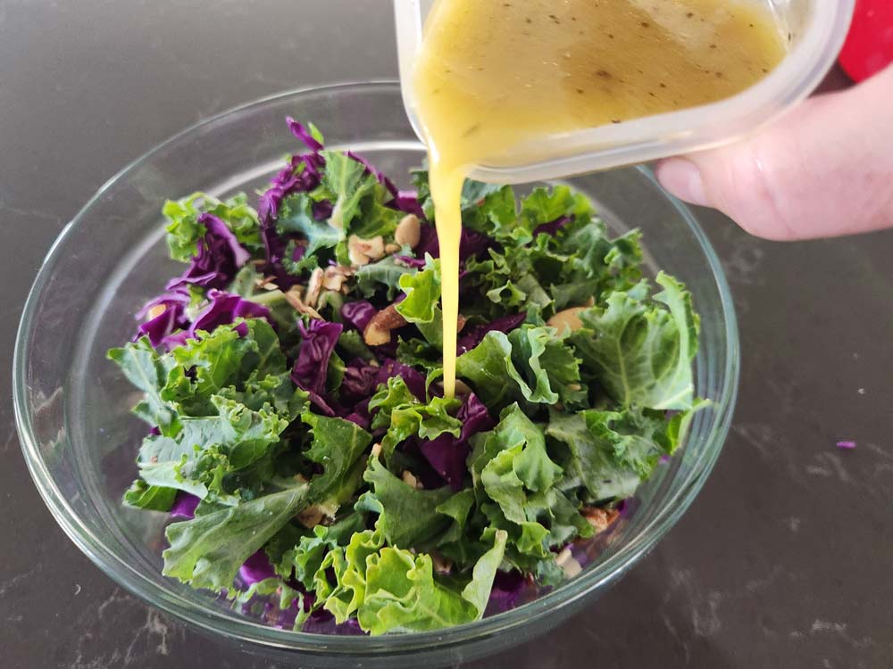 Pouring dressing on kale crunch salad